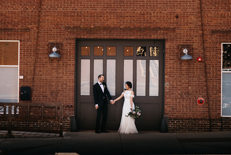 couple posing by brick building couple posing by brick building