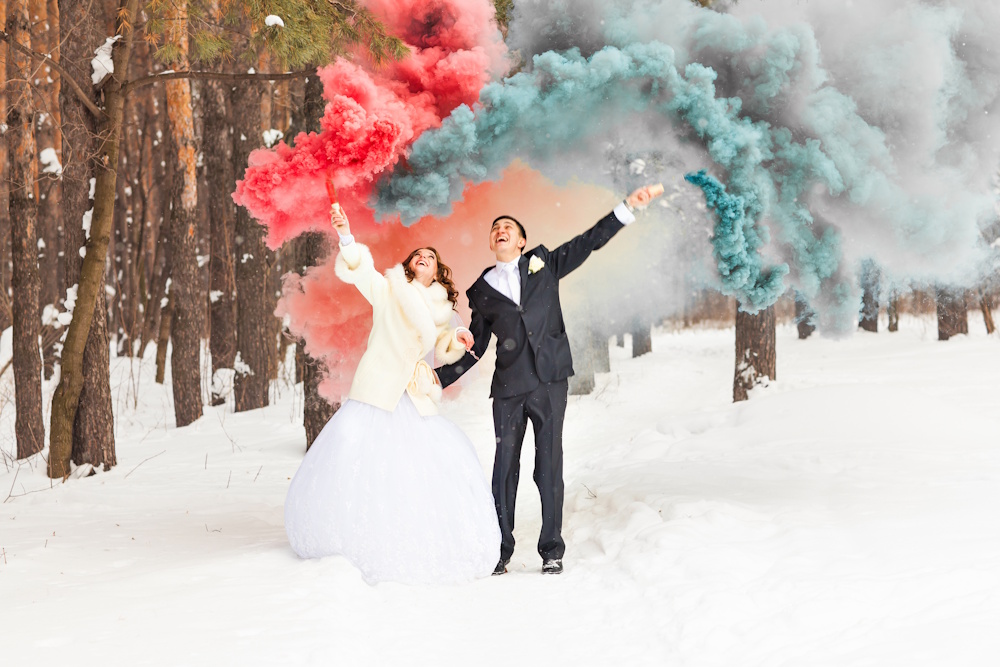 bride and groom with colored smoke in the snow